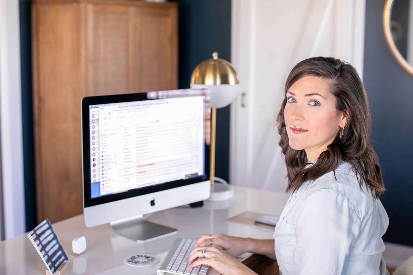 Kate Kordsmeier, a woman with brown hair sitting at her desk in front of a desktop computer.